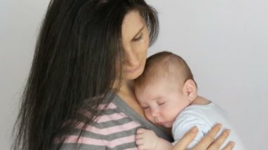 Genç güzel siyah saçlı uzun saçlı anne kucağında yatan iki aylık yeni doğan bebek ile. Anne bebek oğlu beşik