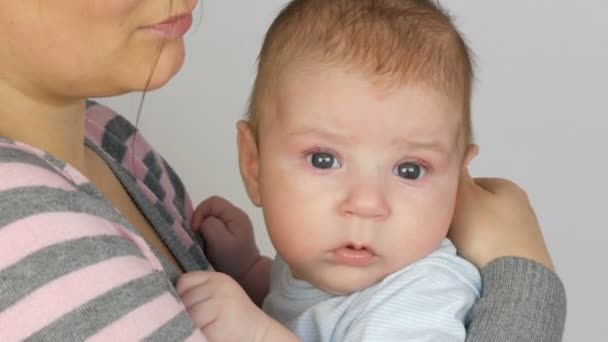 Νεαρή όμορφα μαύρα μαλλιά μακρυμάλλη μητέρα με αστεία δύο-μήνας-παλαιό μωρό νεογέννητο στην αγκαλιά της. Μαμά λικνίζει τον γιο του μωρού — Αρχείο Βίντεο