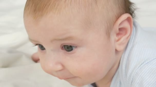 Zwei Monate altes, glückliches Neugeborenes liegt auf dem Bauch auf dem Bett und empfindet Gefühle zu seiner Mutter. Ein Baby lacht, redet, winkt mit den Armen. das Kind mit dem Gesicht aus nächster Nähe — Stockvideo