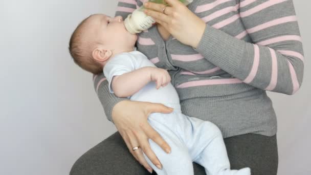 Een twee maanden durende pasgeboren baby ligt aan de armen van de moeder en een tepel zuigt uit fles melk — Stockvideo