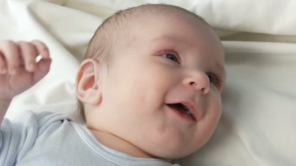 Un nouveau-né heureux de deux mois se couche sur le lit et éprouve des émotions pour sa mère. Un bébé rit, parle, agite les bras. Le visage de l'enfant vue de près — Video