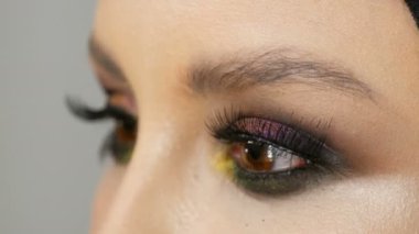 Profesyonel makyöz sahte siyah uzun kirpik farklı renk göz gölgeler ile renkli modeli göz kapalı soyar.
