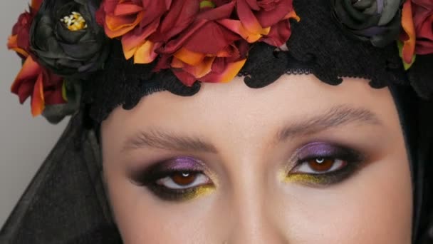 Profi-Model mit wunderschönem Make-up posiert mit schwarzer Mütze und Kranz auf dem Kopf vor der Kamera auf schwarzem Hintergrund im Bild einer schwarzen Witwe. Mode im Trend — Stockvideo