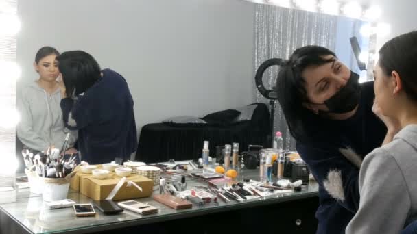 Profesional estilista maquillaje artista compone el ojo humeante de una chica asiática en estudio de visage — Vídeos de Stock
