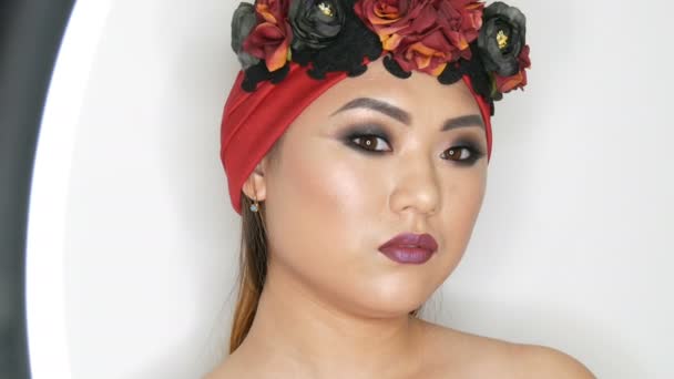 High fashion, portrét krásné asijské dívka s světlý make-up v červeným turbanem a věnec, který vydával v profesionální model studio. — Stock video