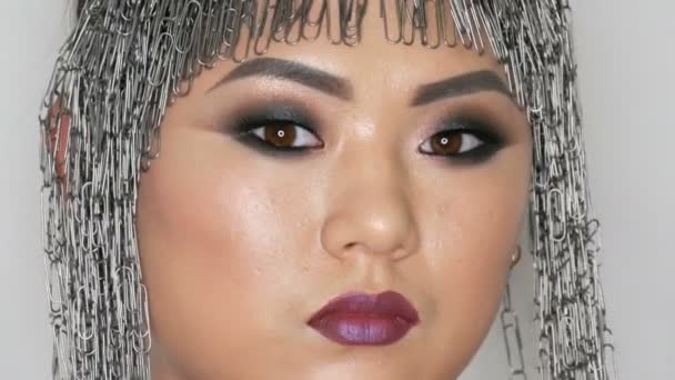 High fashion, portrait of a beautiful Asian girl model with bright makeup and an unusual wig of stationery clips who poses in professional studio. — Stock Video