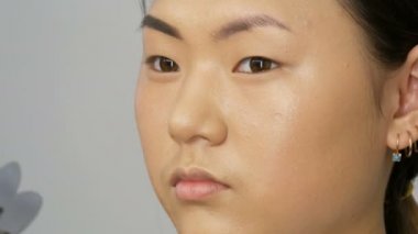 Profesyonel stilist makyöz özel fırçası ile kaş gölgeler bir Asyalı kız modeli yüz görünümü kadar yakın visage Studio ile kaşları boyalar