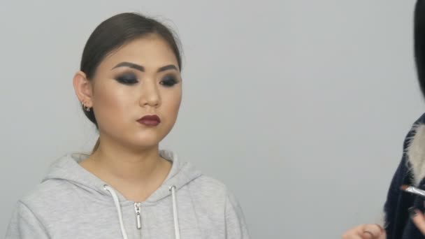 Επαγγελματίας στυλίστας make-up artist κάνει το smoky μακιγιάζ στα μάτια του ένα ασιατικό κορίτσι στο visage studio — Αρχείο Βίντεο