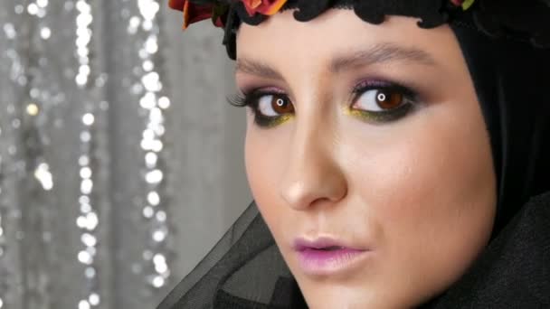 Profesjonalny Model Dziewczyna z pięknym makijażu stwarza w czarnej czapce i wieniec na głowie przed kamerą na srebrnym tle w obrazie czarnej wdowy. Wysoka moda — Wideo stockowe