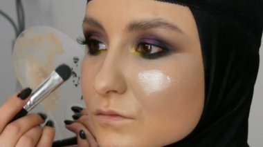 Profesyonel bir sanatçı makyaj için özel fırça ile güzel bir kız modeli, Tüylü toz, vurgulayıcı, temel krem makyaj yapar