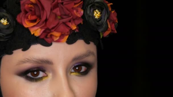 Professionele meisje model met mooie make-up poses in een zwarte pet en een kroon op haar hoofd voor de camera op een zwarte achtergrond in de afbeelding van een zwarte weduwe. Haute Couture — Stockvideo