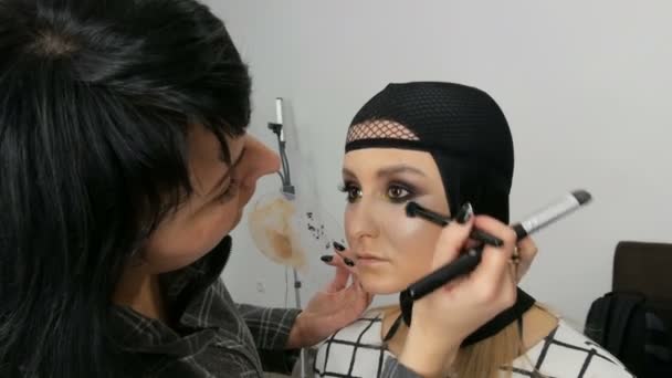 Profesionální umělec vyrábí krásnou dívčí modelku, pečkový prášek, zvýrazňovač, Krémový krém se speciálním kartáčkem na makeup — Stock video