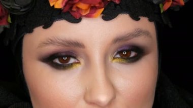 Güzel makyaj ile profesyonel kız modeli siyah kap ve çelenk başında bir karadul görüntüdeki siyah arka plan üzerine kamera önünde poz veriyor. Yüksek moda