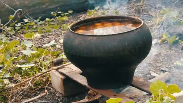 Ogromny garnek z ziemniakiem, który jest gotowane na ogień na zewnątrz — Wideo stockowe