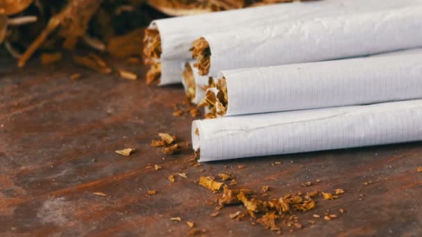 Házi cigaretta vagy roll-up töltött dohány van egy asztal mellett száraz dohánylevelek — Stock videók