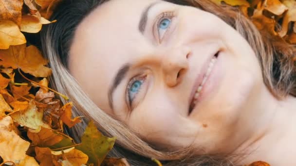 Nahaufnahme Porträt des Gesichts des schönen jungen Mädchens ohne Make-up, das im herbstgelben Laub liegt und das Leben genießt — Stockvideo