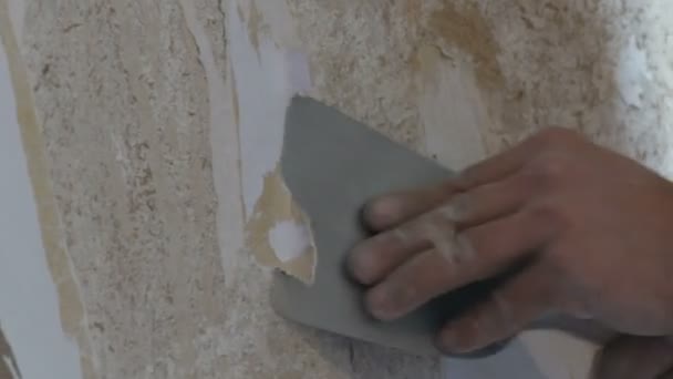 Man cleans the clay walls of old wallpaper with a spatula close up view — Stock Video