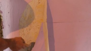 Erkek inşaatçılar el akıntılar ya da özel bir spatula ile duvar eski pembe duvar kağıdı kabuğu