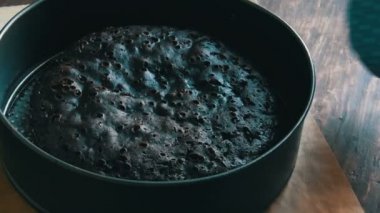 Mavi mutfak eldiveni kadın elinde taze pişmiş ev yapımı çikolatalı browni kek masanın üzerine alır.