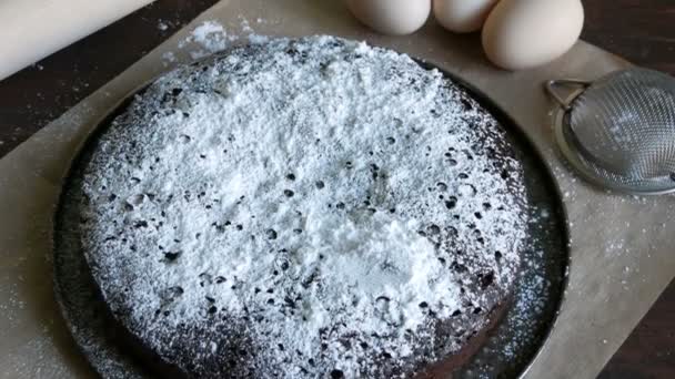 Hausgemachte gebackene Schokolade Brownie Muffin mit Zucker vor einem Hintergrund von Eiern und Nudelholz gepudert — Stockvideo