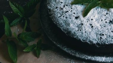 Şık ev yapımı fırında çikolatalı browni kek cömertçe bir pudra şekeri yanında taze nane yaprakları ile toz.
