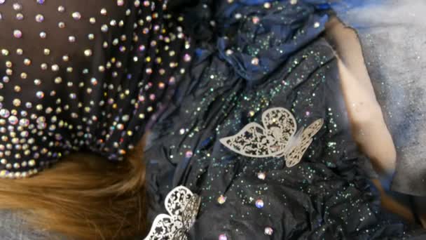 Di alta moda. Designer prepara l'immagine di una ragazza aliena modello in una maschera nera in strass scintillanti, scintille, farfalle di metallo in studio in — Video Stock