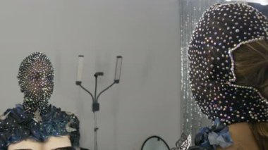 Yüksek moda. Parlak Rhinestones, parıltılı, siyah ve gümüş arka plan üzerinde siyah bir maske bir uzaylı kız görüntüde model ayna önünde poz renkli bir fotoğraf