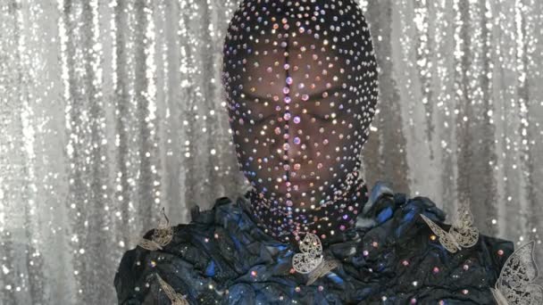 Yüksek moda. Bir model stüdyosunda poz siyah ve gümüş arka planda parlayan Rhinestones, parıltılı, metal kelebekler siyah bir maske bir uzaylı kız görüntü modeli. — Stok video