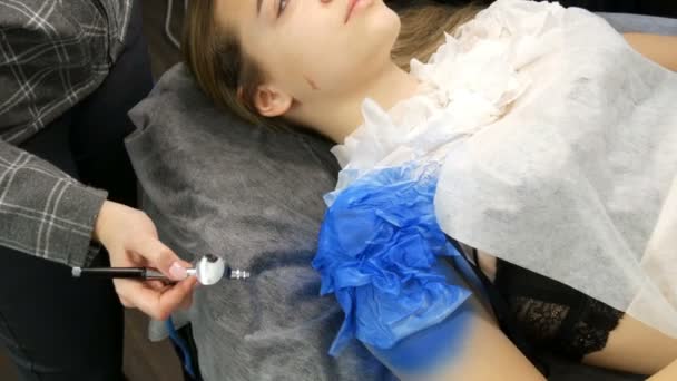 Moda Stüdyosu, model gösterisi için hazırlanıyor. Genç kız özel bir kanepede yatıyor, tasarımcı mavi boya ile özel bir Airbrush sprey kullanarak onu görüntü hazırlar — Stok video