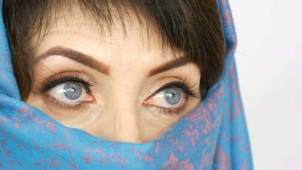 Retrato de una mujer adulta árabe de mediana edad con unos ojos azules hermosos e inusuales con pestañas largas en paño islámico tradicional niqab o burka azul. Primer plano de la hermosa mujer musulmana — Vídeos de Stock