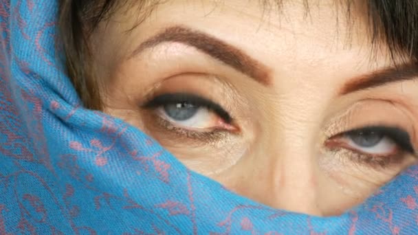 Portrait d'une femme adulte arabe d'âge moyen avec de beaux grands yeux bleus inhabituels avec de longs cils en tissu islamique traditionnel niqab ou burqa bleu. Gros plan de belle femme musulmane — Video