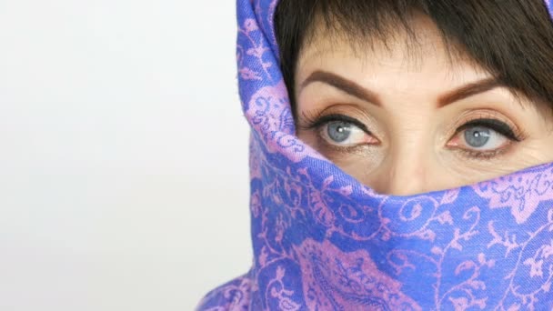 Retrato de una mujer árabe adulta de mediana edad con ojos azules grandes e inusuales con pestañas largas en paño islámico tradicional niqab o burka. Primer plano de la hermosa mujer musulmana — Vídeos de Stock