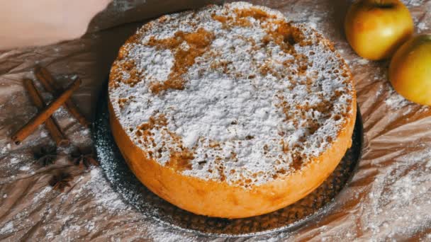 Délicieuse tarte aux pommes Charlotte fraîchement cuite saupoudrée de sucre en poudre avec vue sur le dessus de la main femme — Video