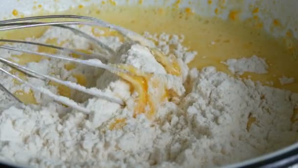 Cozinha mão metal batedor chicotes massa para bolo caseiro em uma tigela vista de perto — Vídeo de Stock