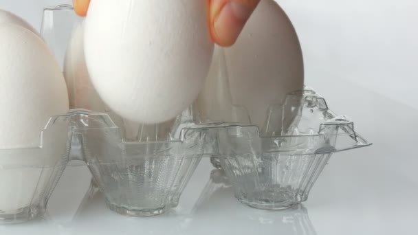 Huevos de pollo blancos grandes en bandeja de plástico transparente sobre un fondo blanco — Vídeo de stock