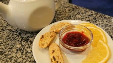 Kurabiye, limon dilimleri ve Berry Jam yanında, porselen beyaz Çaydanlık ve daire çay seti