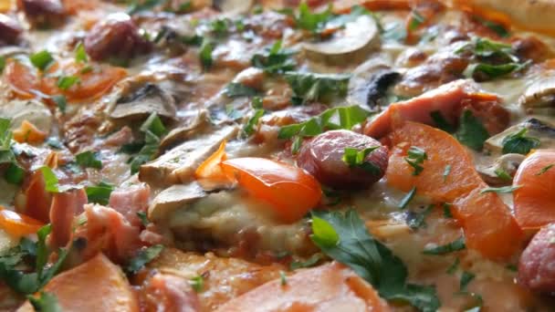 A large freshly baked pizza with which there is steam, a close view. Delicious pizza with tomato, greens, Bavarian sausages, mushrooms, bacon. — Stock Video