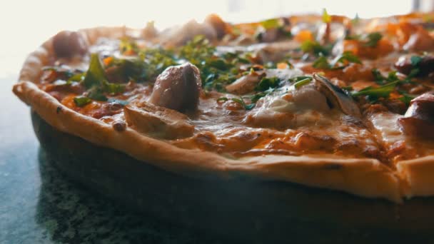 A nagy, frissen sült pizzát, amely a gőz, a közeli kilátás. Ízletes pizza paradicsom, zöldek, bajor kolbász, gomba, bacon. — Stock videók