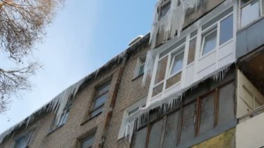 Eski terk edilmiş ev ve kış aylarında büyük miktarda erime buz sarkıtları ile balkon.