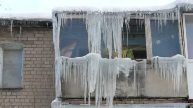 Eski terk edilmiş ev ve kış aylarında büyük miktarda erime buz sarkıtları ile balkon.
