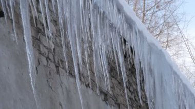 Kışın evin çatısında büyük erime buz sarkıtları çok sayıda