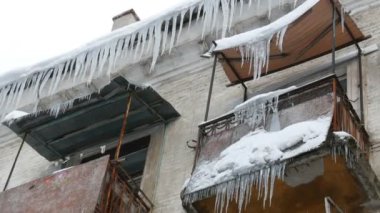 Eski terk edilmiş ev ve kış aylarında büyük miktarda erime buz sarkıtları ile balkon.