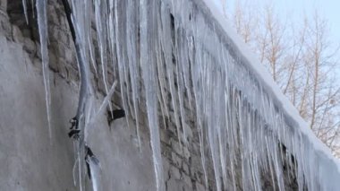 Kışın evin çatısında büyük erime buz sarkıtları çok sayıda