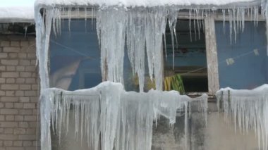Eski terk edilmiş ev ve kış aylarında büyük miktarda erime buz sarkıtları ile balkon.