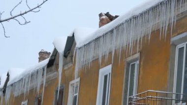 Kışın evin çatısında büyük erime buz sarkıtları çok sayıda