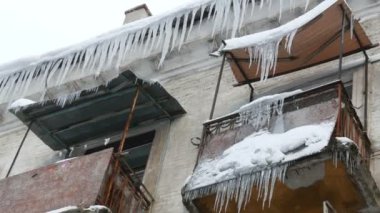 Eski terk edilmiş ev ve kış aylarında büyük miktarda erime buz sarkıtları ile balkon.
