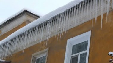 Kışın evin çatısında büyük erime buz sarkıtları çok sayıda
