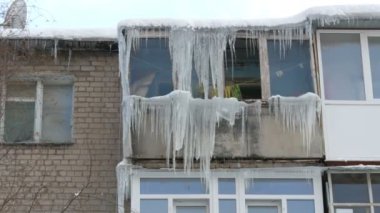 Eski terk edilmiş ev ve kış aylarında büyük miktarda erime buz sarkıtları ile balkon.