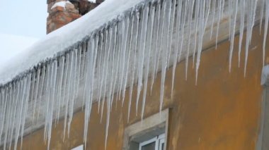Kışın evin çatısında büyük erime buz sarkıtları çok sayıda