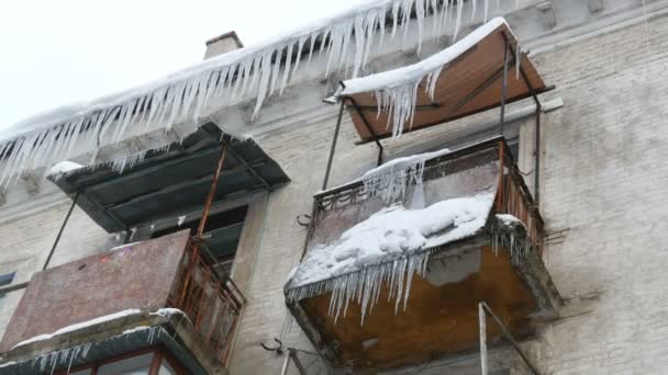 Eski terk edilmiş ev ve kış aylarında büyük miktarda erime buz sarkıtları ile balkon. — Stok video